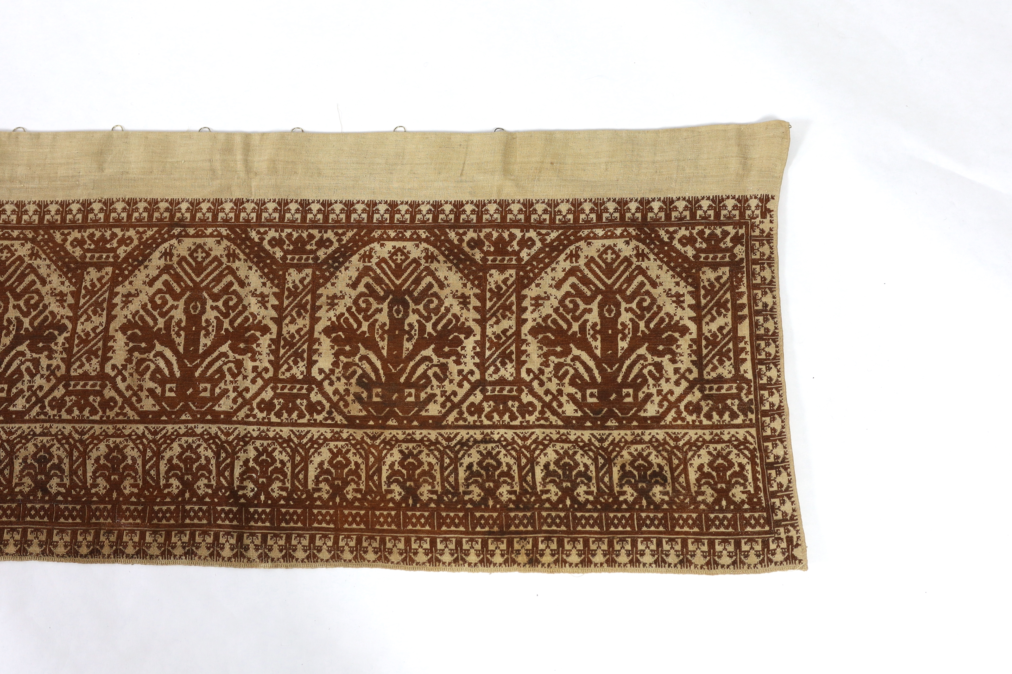 An early 19th century long Greek Islands cross stitch pelmet (hanging), embroidered on coarse linen with brown silk, using cross stitch, designed in horizontal rows of similar symbols, the lower row being a smaller size,